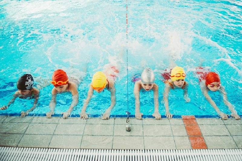 Les enfants heureux se regroupent en classe de piscine pour apprendre à nager.